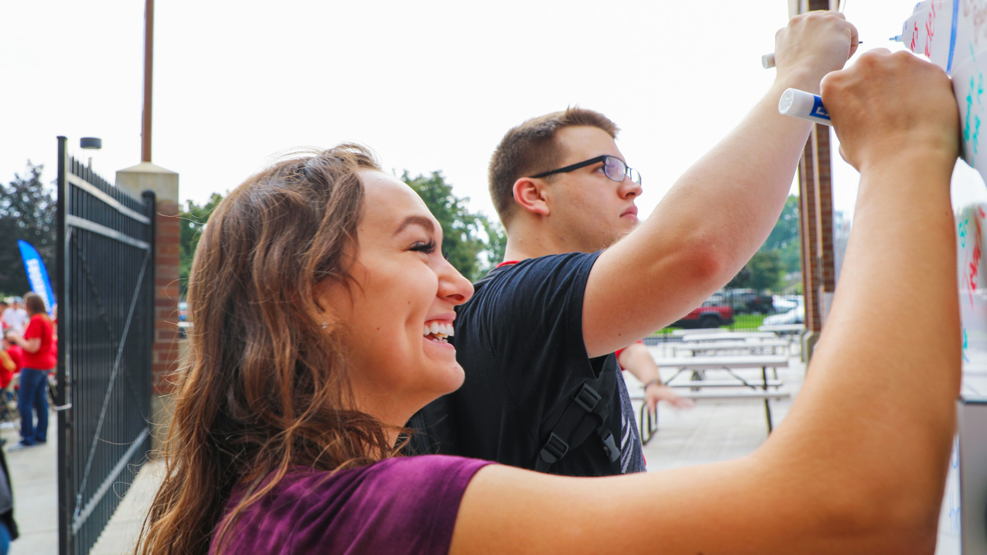 Female student writing on a white board outside